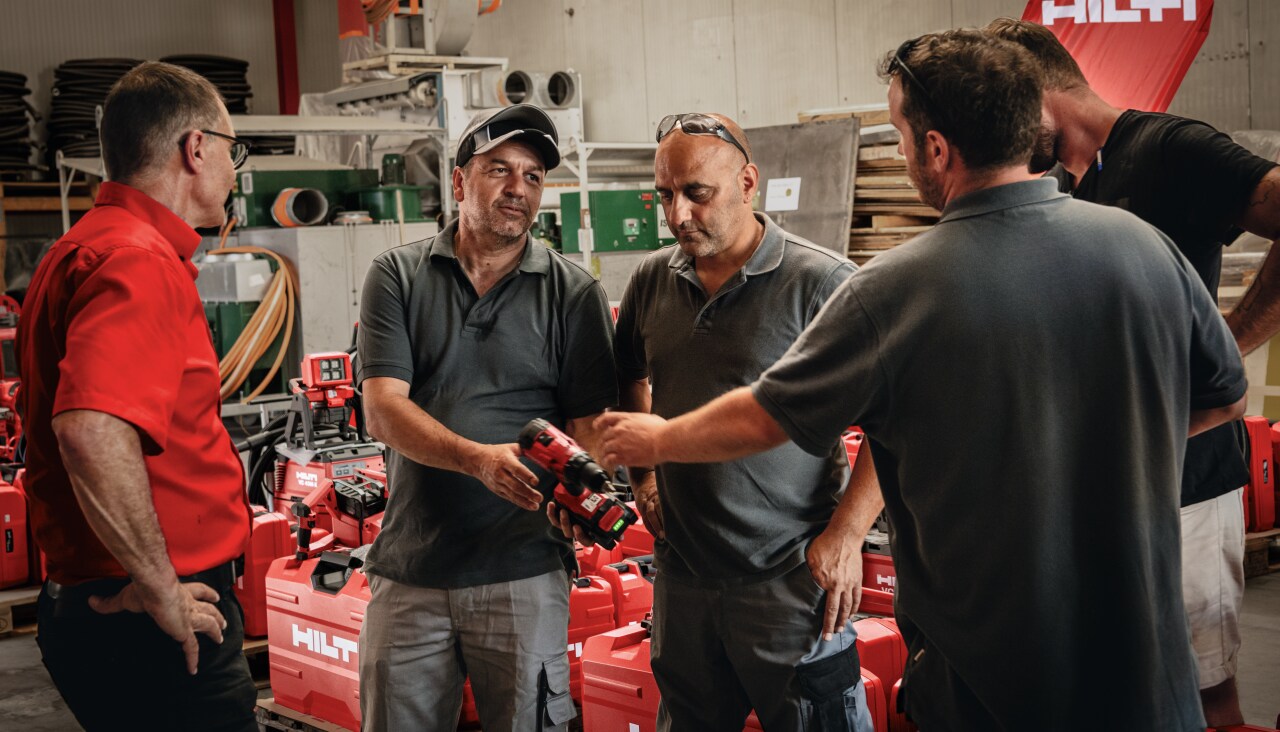 Un chargé d'affaires Hilti avec des clients qui tiennent une visseuse