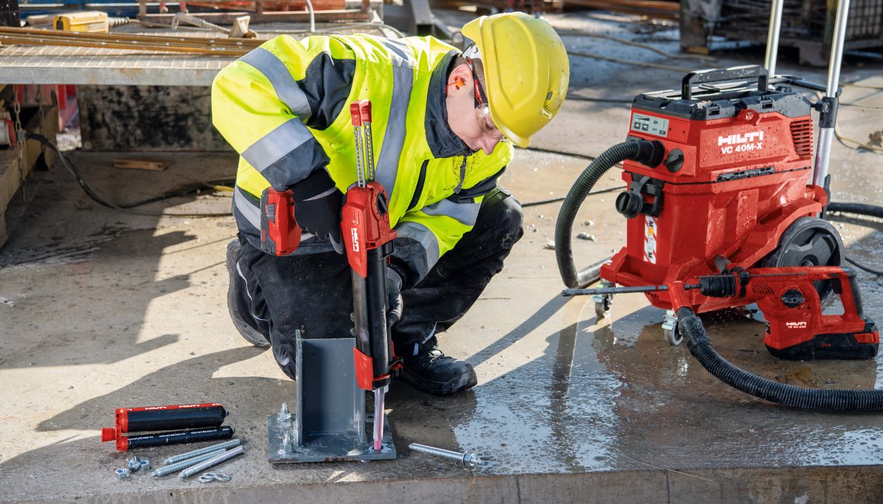 Un ouvrier sur chantier injecte de la résine dans une platine à l'aide du pistolet de scellement HDE 500-A22