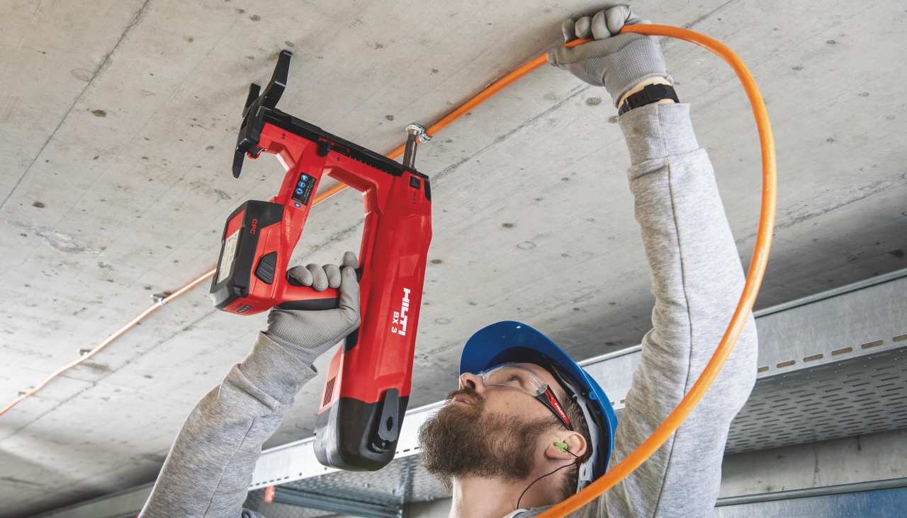 Fixation d'une gaine électrique au plafond à l'aide du cloueur sur batterie BX 3