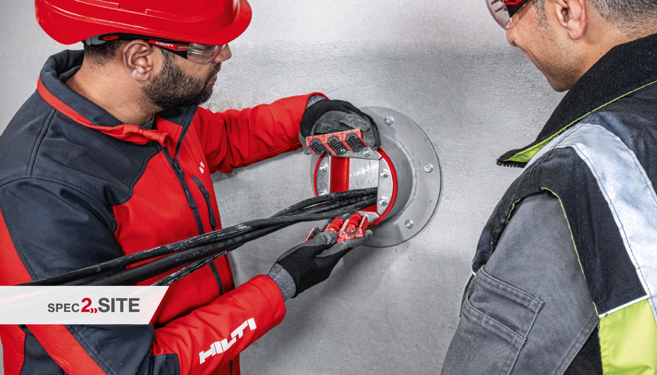 un ingénieur de terrain Hilti montre à un client un manchon coupe-feu dans une application électrique