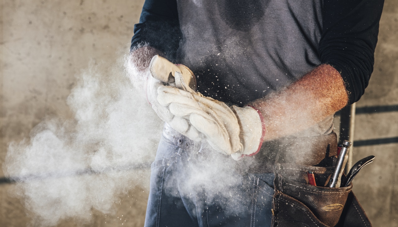 Un ouvrier se frotte les mains pour dégager de la poussière